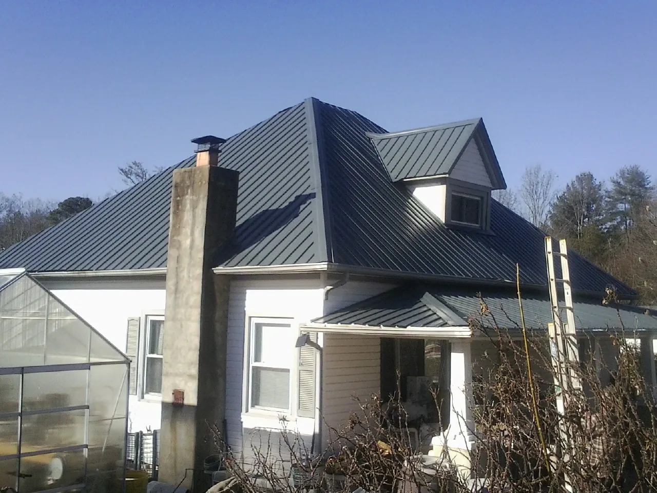 Dark blue standing seam metal roof on a white farmhouse with dormer — Slate & Tile Roof Repair by Roofing Brothers in Great Valley