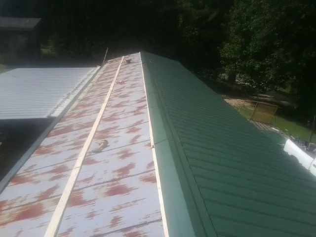 Old rusted panels beside newly installed green metal roofing — Wind Damage Roof Repair by Roofing Brothers in Great Valley