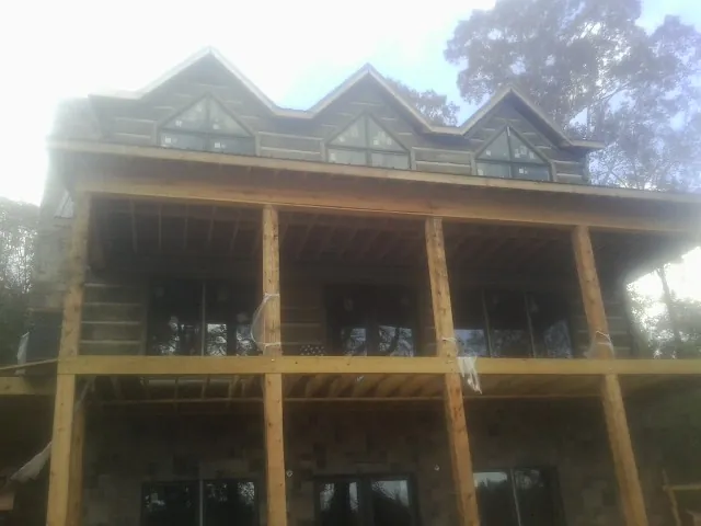 Dormers and porch framing on a large log home under construction — Roof Coating work by our crew in Great Valley