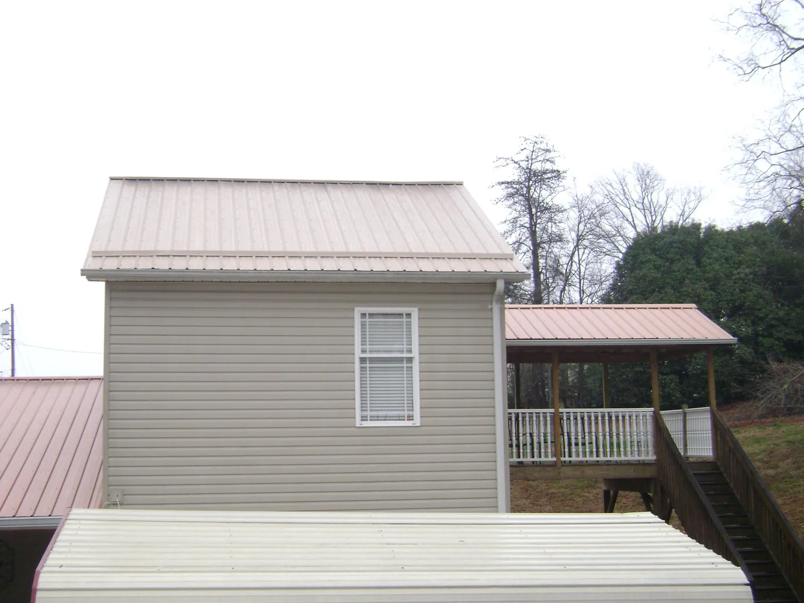 Tan metal roofs on a two story addition and attached porch, from a Roof Replacement job in Great Valley