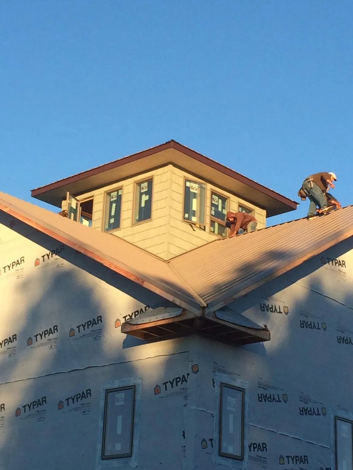 Roofers working around a rooftop cupola on a new metal roof at sunset — Roof Waterproofing in Great Valley by Roofing Brothers